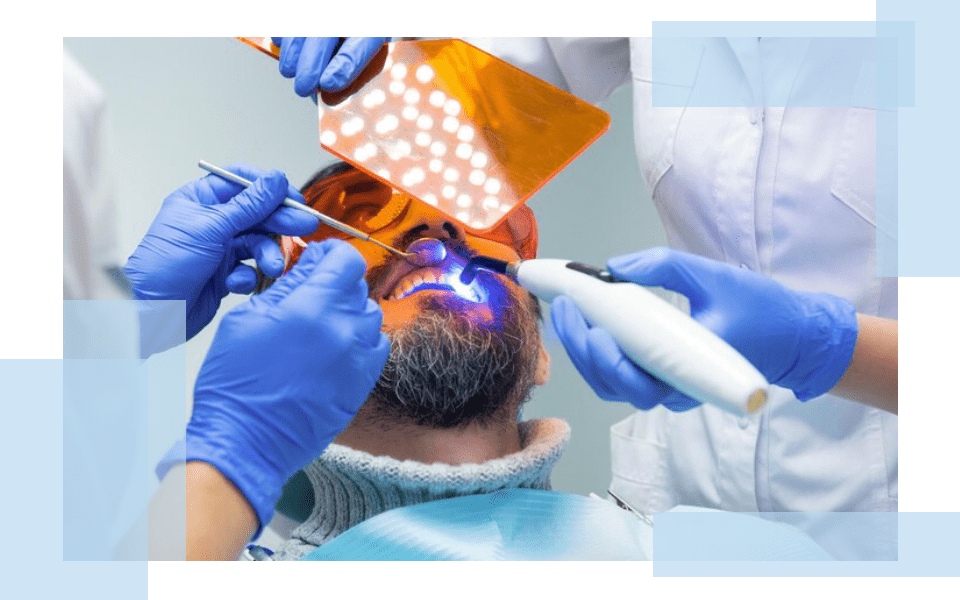 A man getting his teeth cleaned by two dentists.