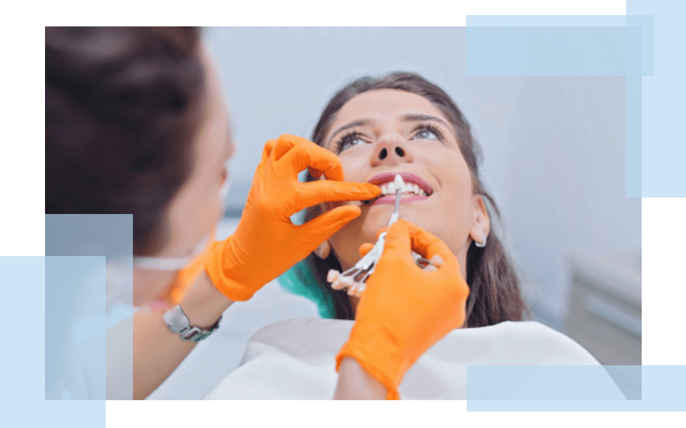 A woman is getting her teeth brushed by an orange glove.